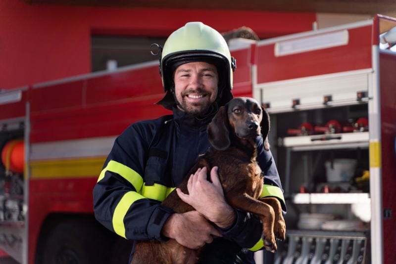 Happy firefighter man holding dog