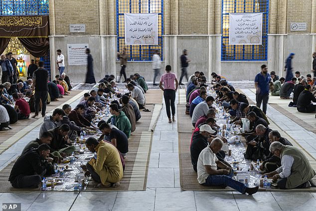 Muslims sit together to enjoy a free public Iftar meal during the first day of Ramadan at Sheikh Abdul qader Gilani mosque in Baghdad, Iraq
